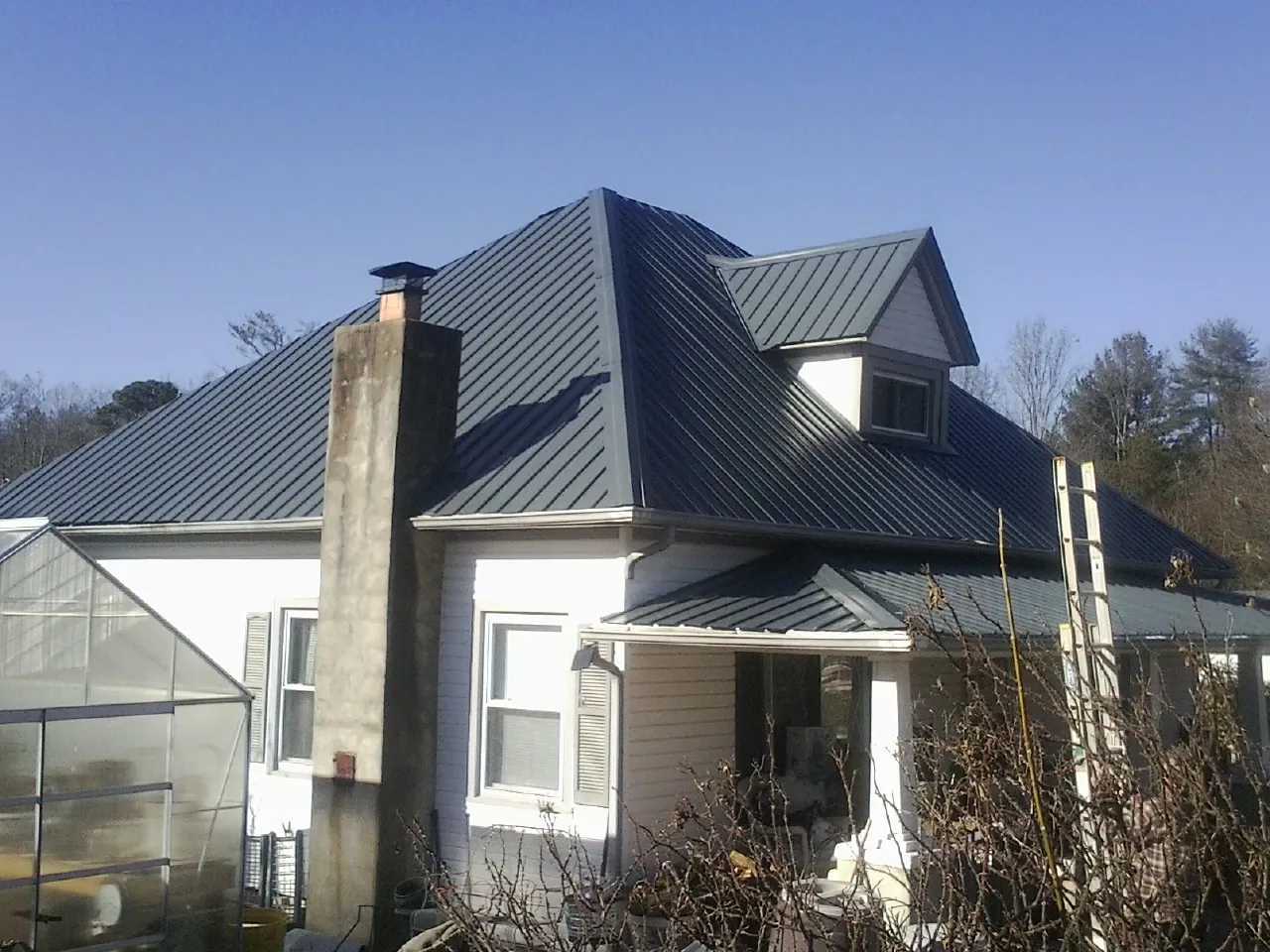 Dark blue standing seam metal roof on a white farmhouse with dormer — Slate & Tile Roof Repair by Roofing Brothers in Hurricane