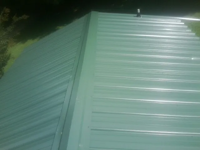 New green metal panels meeting at the ridge of a roof — Flat Roof Repair work by our crew in Hurricane